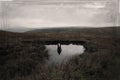 A mysterious silhouette of a man reflected in water with no one above on a bleak moorland hillside. With a retro, grunge, blurred