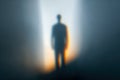 Mysterious silhouette of a person standing in the distance against a backdrop of soft glowing light and deep shadow creating an Royalty Free Stock Photo