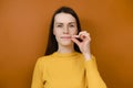 Mysterious smiling woman looks mysteriously, aside zips her mouth shut, promises to keep secret, holds fingers near cheek Royalty Free Stock Photo