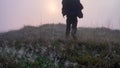 A mysterious spooky figure running towards the sun, out of focus with a shallow depth of field in the background. With a close up