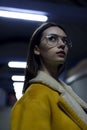 Mysterious stylish brunette in jacket and glasses, posing for womenswear fashion. City lights by night