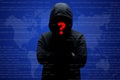 Mysterious unknown hacker in black clothing with hoodie, stands crossed hands against dark digital interface background with red q