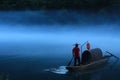 Mysterious view of a man on the wooden boat rowing on the misty lake Royalty Free Stock Photo