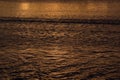 Mysterious waves of water in golden sunbeams on sunset, abstract background. Royalty Free Stock Photo
