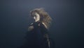 Mysterious woman in black dress swimming like mermaid under water in dark pool