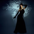 Mysterious Woman in long Black Dress perform on Art Stage. Lady in evening Gown over Shadow Background. Beautiful Girl dancing Royalty Free Stock Photo