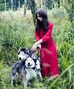 Mysterious woman in red dress with tree wolfs, forest, husky dogs mystery portrait