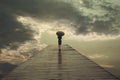 Mysterious woman with umbrella crosses a bridge to the threatening sky Royalty Free Stock Photo