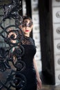 Mysterious woman in venetian carnival mask near wrought iron gate Royalty Free Stock Photo