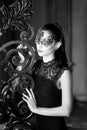 Mysterious woman in venetian carnival mask near wrought iron gate. Noir style Royalty Free Stock Photo