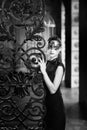 Mysterious woman in venetian carnival mask near wrought iron gate. Noir style Royalty Free Stock Photo