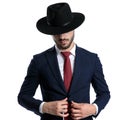 Mysterious young businessman adjusting his jacket while wearing a hat Royalty Free Stock Photo