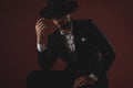 Mysterious young man wearing tuxedo and arranging hat