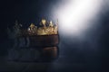 Mysteriousand magical image of old crown and book over gothic black background. Medieval period concept.