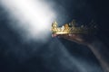 Mysteriousand magical image of woman`s hand holding a gold crown over gothic black background. Medieval period concept. Royalty Free Stock Photo