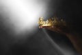 Mysteriousand magical image of woman`s hand holding a gold crown over gothic black background. Medieval period concept. Royalty Free Stock Photo