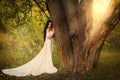 Mystery art portrait fantasy woman in white vintage style dress. queen walking in summer forest hand touching tree. Girl Royalty Free Stock Photo