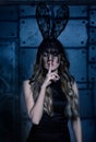 The mystery of Black Rabbit. Young woman in black rabbit fancy dress, with closed eyes and finger on lips