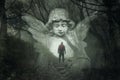 A mystery concept of a hiker lost in a spooky winters forest. With a double exposure of a graveyard angel over the top. With a