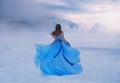 Mystery fantasy Woman Snow Queen in blue lush dress, fly in wind. Lady traveler. Art background winter frozen nature