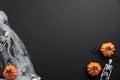 Mystery Halloween background with pumpkins, spiderwebs, skeletons, spiders on black table. Flat lay, top view, copy space Royalty Free Stock Photo