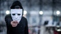 Mystery hoodie man with black mask holding white mask in his hand. Anonymous social masking or bipolar disorder concept