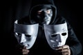 Mystery man in black mask holding white masks Royalty Free Stock Photo