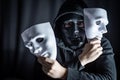 Mystery man in black mask holding white masks Royalty Free Stock Photo