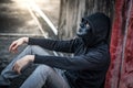 Mystery man in black mask sitting in abandoned building feeling