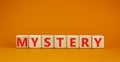 Mystery symbol. The concept word Mystery on wooden cubes. Beautiful orange table, orange background, copy space. Business and Royalty Free Stock Photo