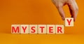 Mystery symbol. The concept word Mystery on wooden cubes. Beautiful orange table, orange background, copy space. Businessman hand Royalty Free Stock Photo