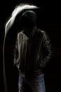 Mystic black hooded man standing in the darkness.