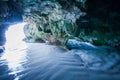 Mystic cave by the sea, view from inside the cave looking out, sunbeam shines down on ripple sand beach into the cave Royalty Free Stock Photo