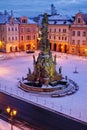 The mystical atmosphere of a historic city with snow and a baroque plague column and statues and lamp in