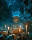 Mystical blue flame in an ornate chalice surrounded by candles in a cave