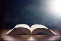 Mystical book on wooden table with light shine and dust