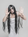 Mystical ghost woman in white long shirt with hands up on gray Royalty Free Stock Photo