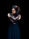 Mystical lady in a black dress with makeup with flowers in her hair on a black background. Magic black, Gothic beauty, mystical
