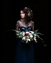 Mystical lady in a black dress with makeup with flowers in her hair on a black background. Magic black, Gothic beauty, mystical