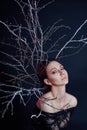 Mystical portrait of an Armenian woman with big blue eyes and branches behind. Lovely gorgeous girl posing in evening dress