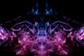 Mystical silhouette of evaporating ghost head smoke on a black background in thin tongues of blue flame highlighted in pink