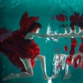 Mystical underwater portrait of a beautiful young woman in a red dress. Royalty Free Stock Photo