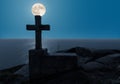 The full moon over the Atlantic and in the foreground a stone cross in Finisterre. Royalty Free Stock Photo