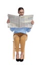 Mystified woman reading newspaper on white background