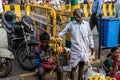 An elderly Indian street vendor with a young boy selling bananas on the pavement