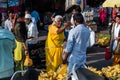 An Indian female street vendor wearing a yellow sari haggling with a customer at a Royalty Free Stock Photo