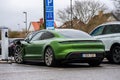 Green electric Porsche Taycan charging at a parking lot..