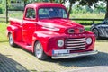 An old renovated red Ford vintage pickup in a parking lot.