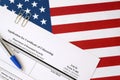 N-600 Application for Certificate of Citizenship blank form lies on United States flag with blue pen from Department of Homeland