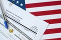 N-400 Application for Naturalization and Certificate of naturalization lies on United States flag with blue pen from Department of